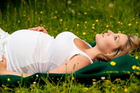 Pregnant woman laying in grass